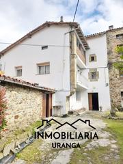 Casa  El puente. Casa de piedra adosada con jardín y edificaciones auxiliares en