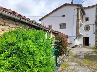 Casa  El puente. Casa de piedra adosada con jardín y edificaciones auxiliares en