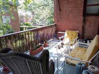 Pis a Neguri. Salón con chimenea, biblioteca y salida a una terraza cerrada.